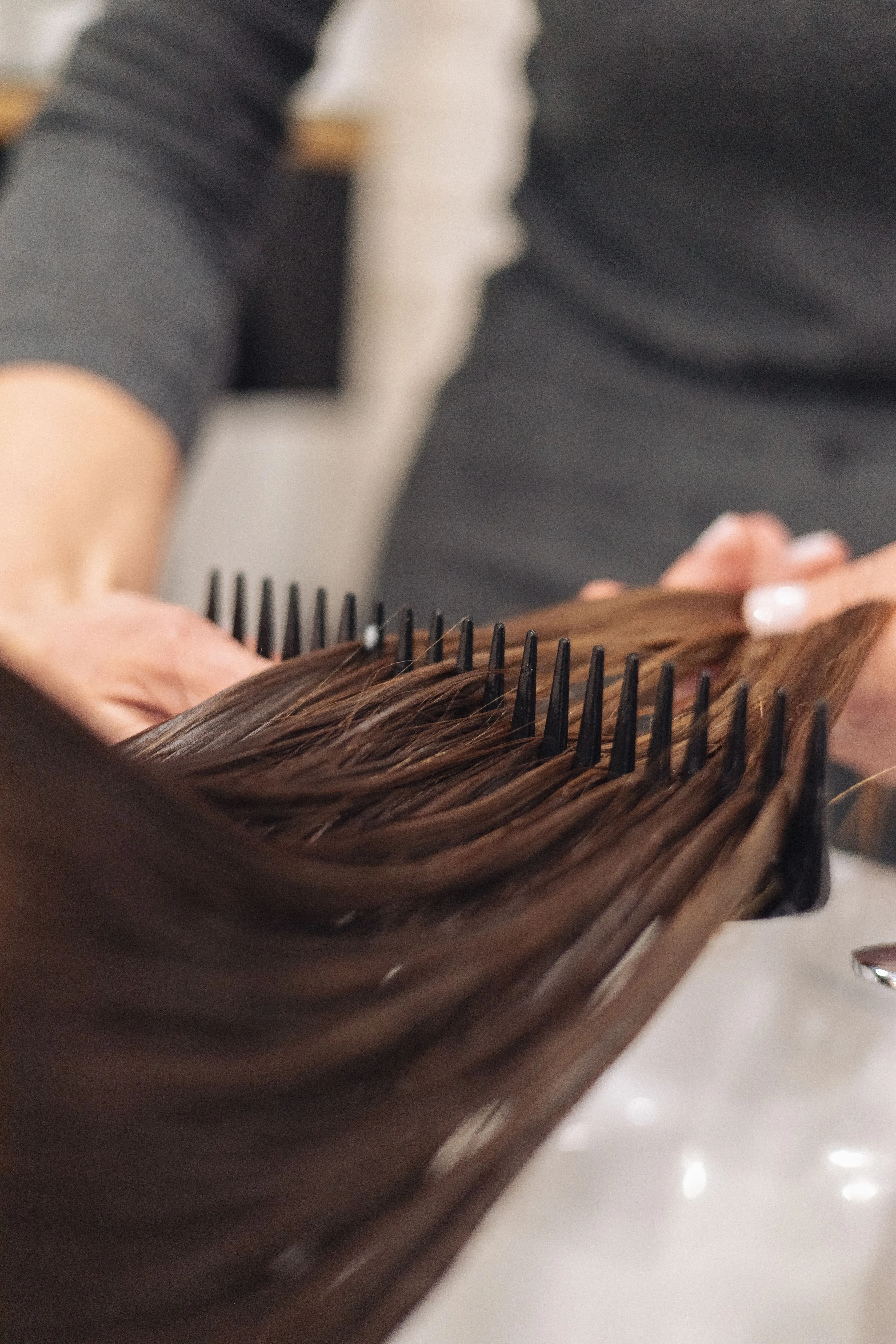 Stylist combing through a client's hair at Shear Temptation
