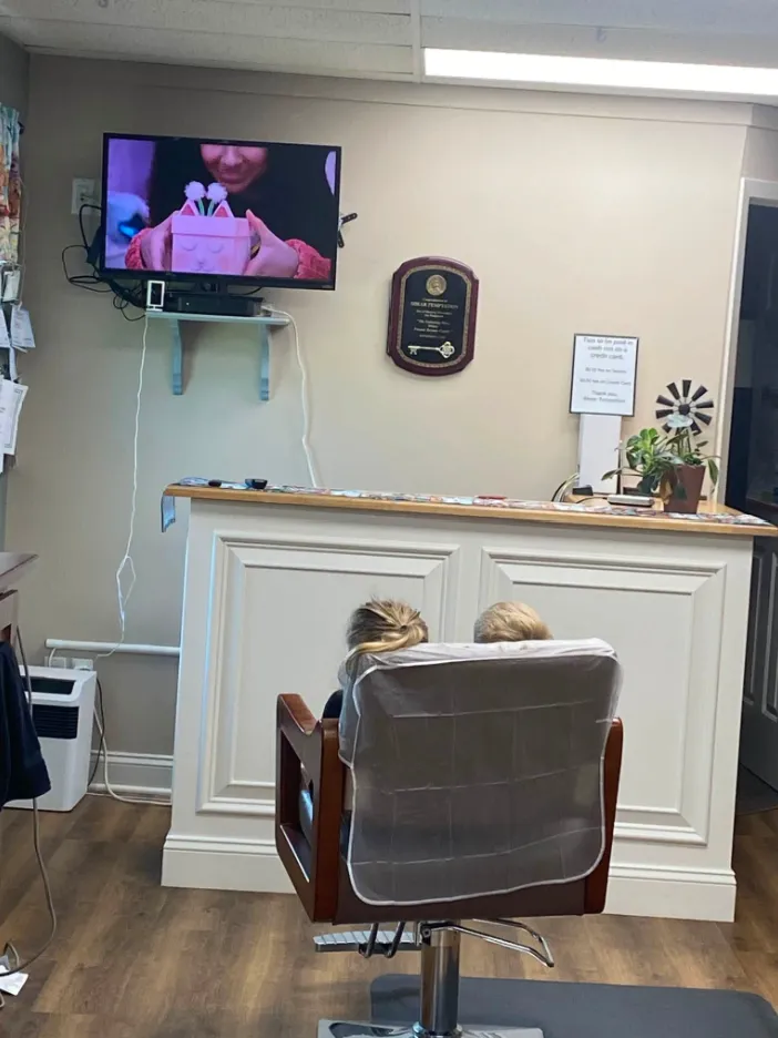 Kids getting haircuts side by side, watching cartoons